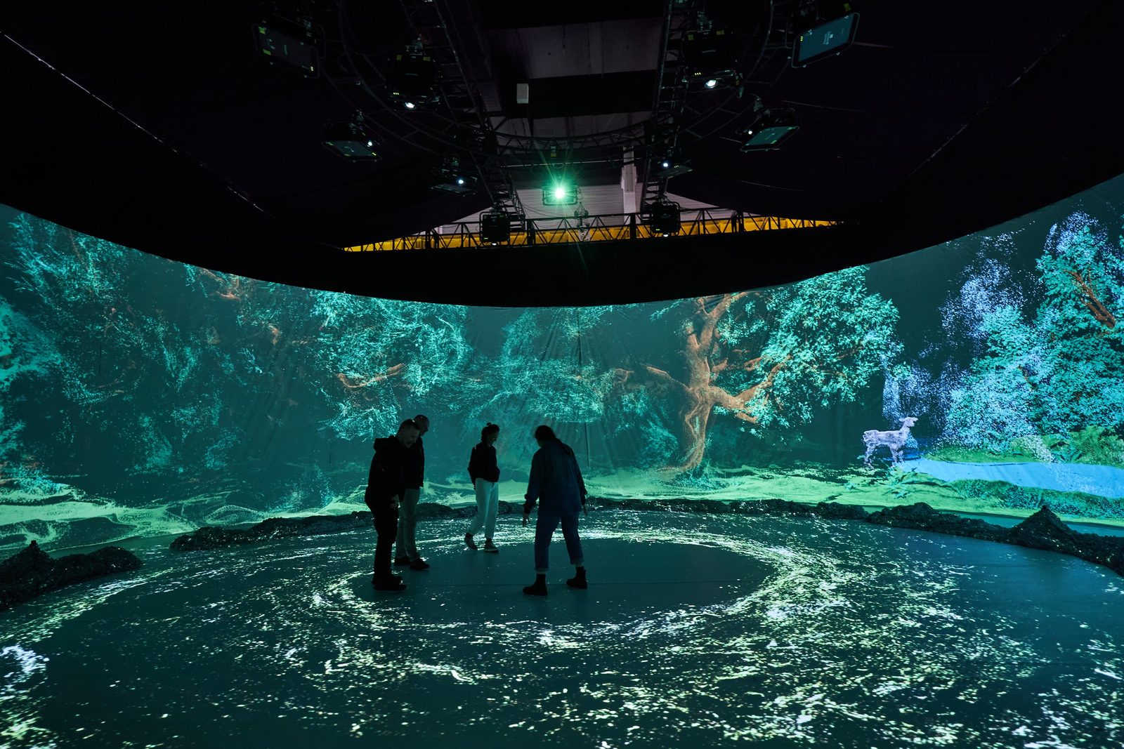 Visitors standing inside a four-sided immersive projection space