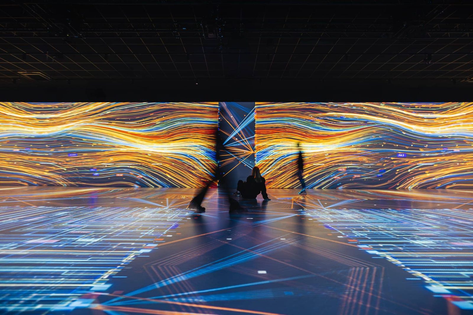 Colorful immersive digital art exhibition with light flowing across walls and floor