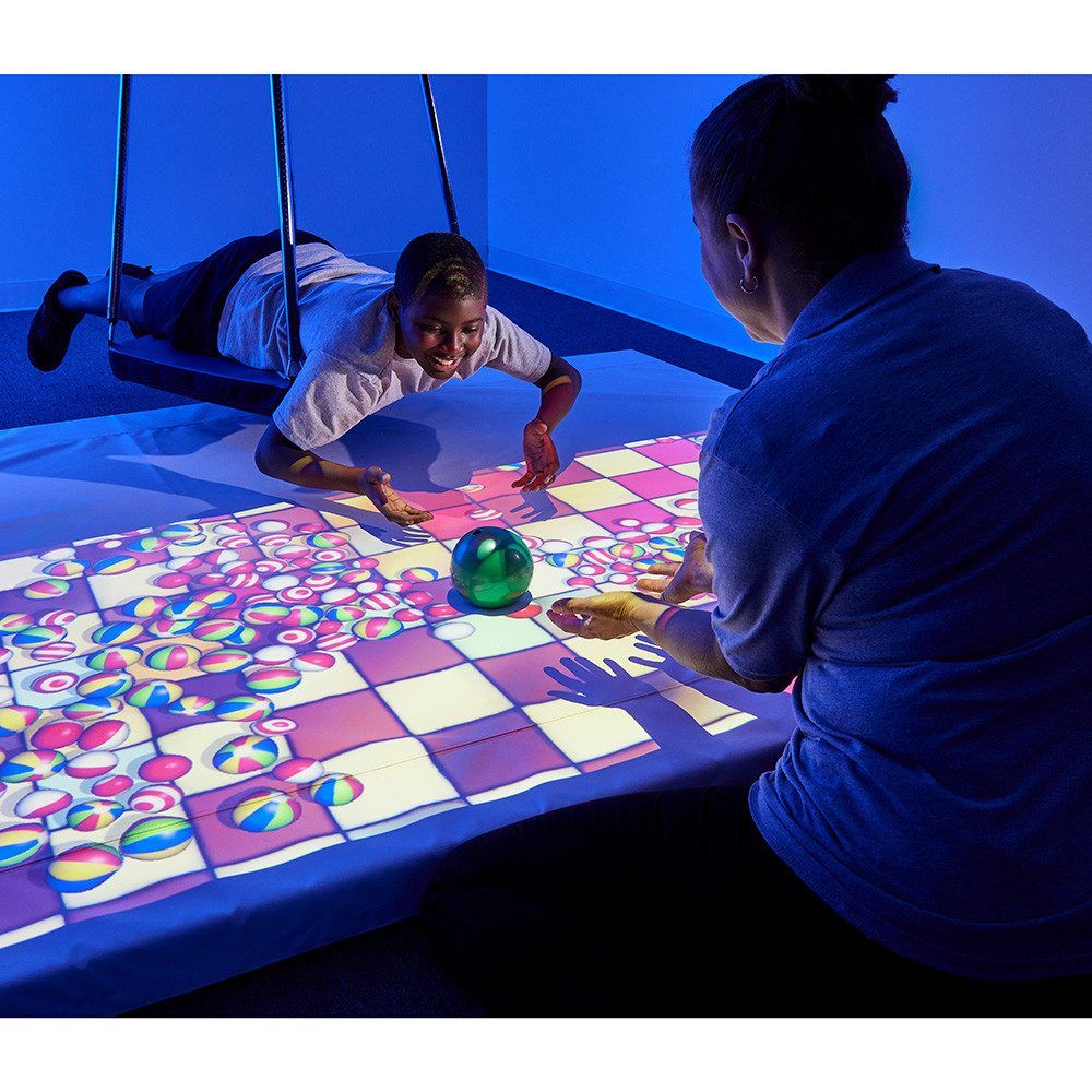 Children playing an interactive projection ball-pool game in a blue sensory room