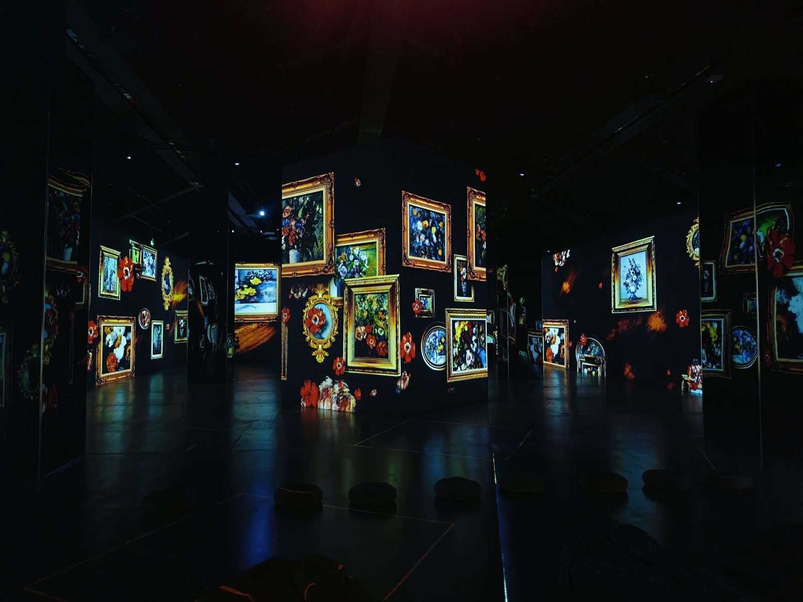 Classical paintings and flower projections arrayed across a showroom wall