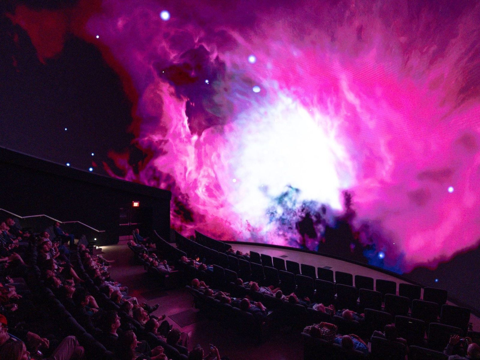 Nebula visuals filling a dome theater, audience seated inside the blended image