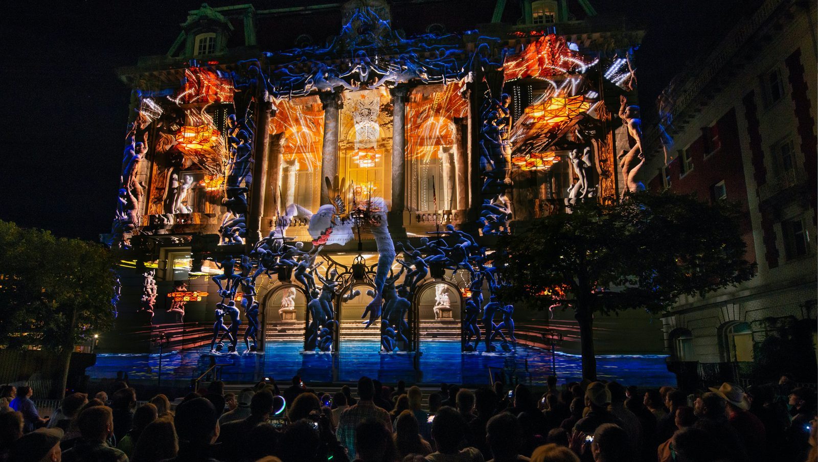 Crowds filming a giant 3D projection show on a historic building facade