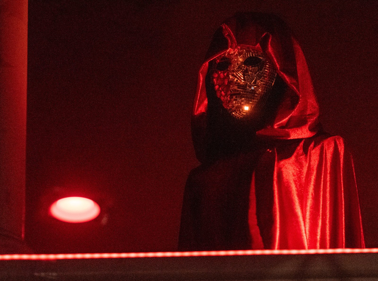 Red-cloaked NPC standing at an immersive horror theater entrance
