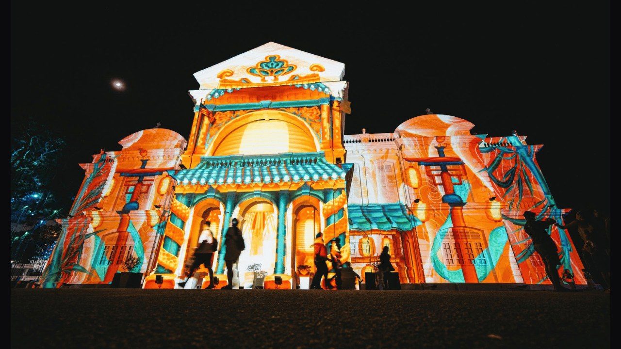 Orange and blue projection art illuminating a colonial-style building facade