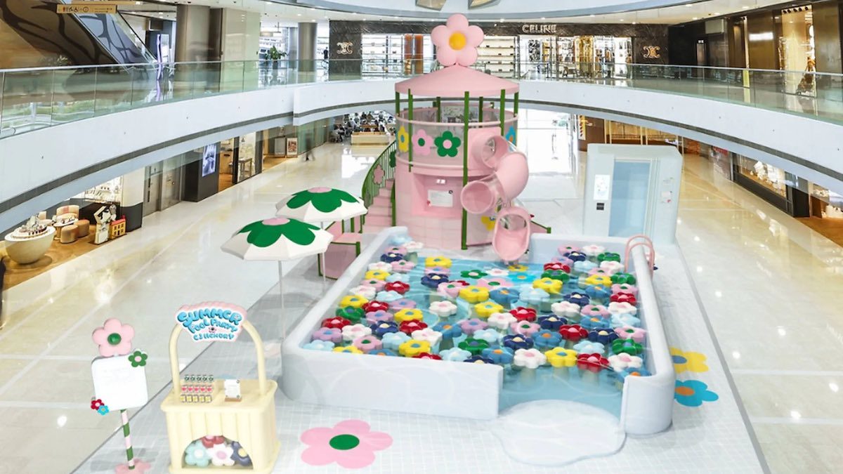Pink flower-themed interactive floor installation drawing families in a mall atrium